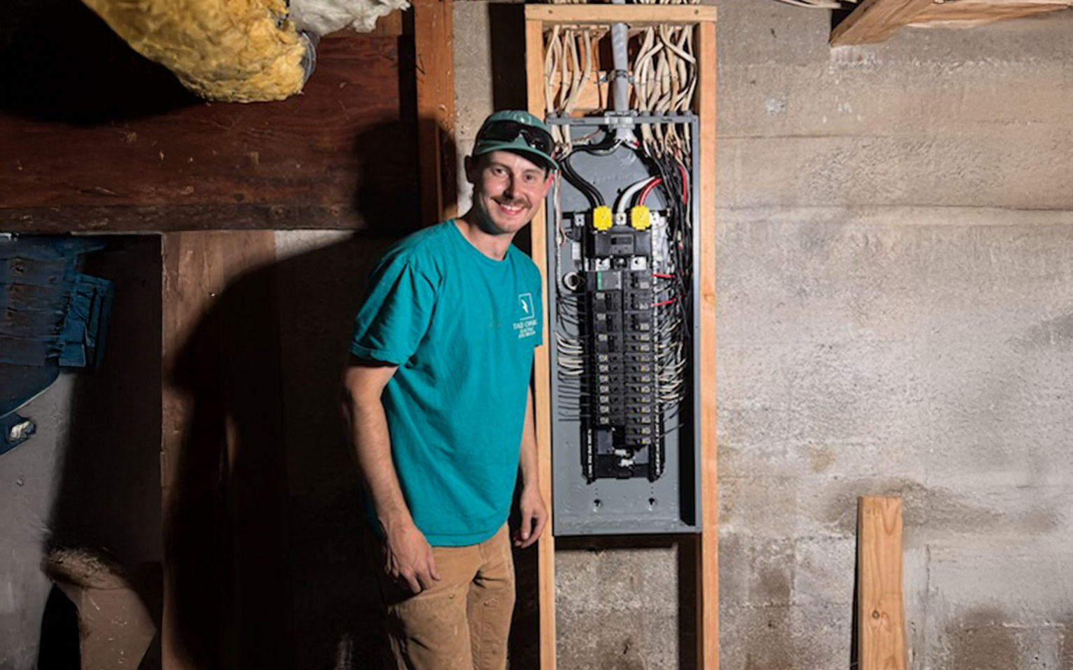 Licensed electrician standing next to an open main breaker panel during a home electrical inspection.