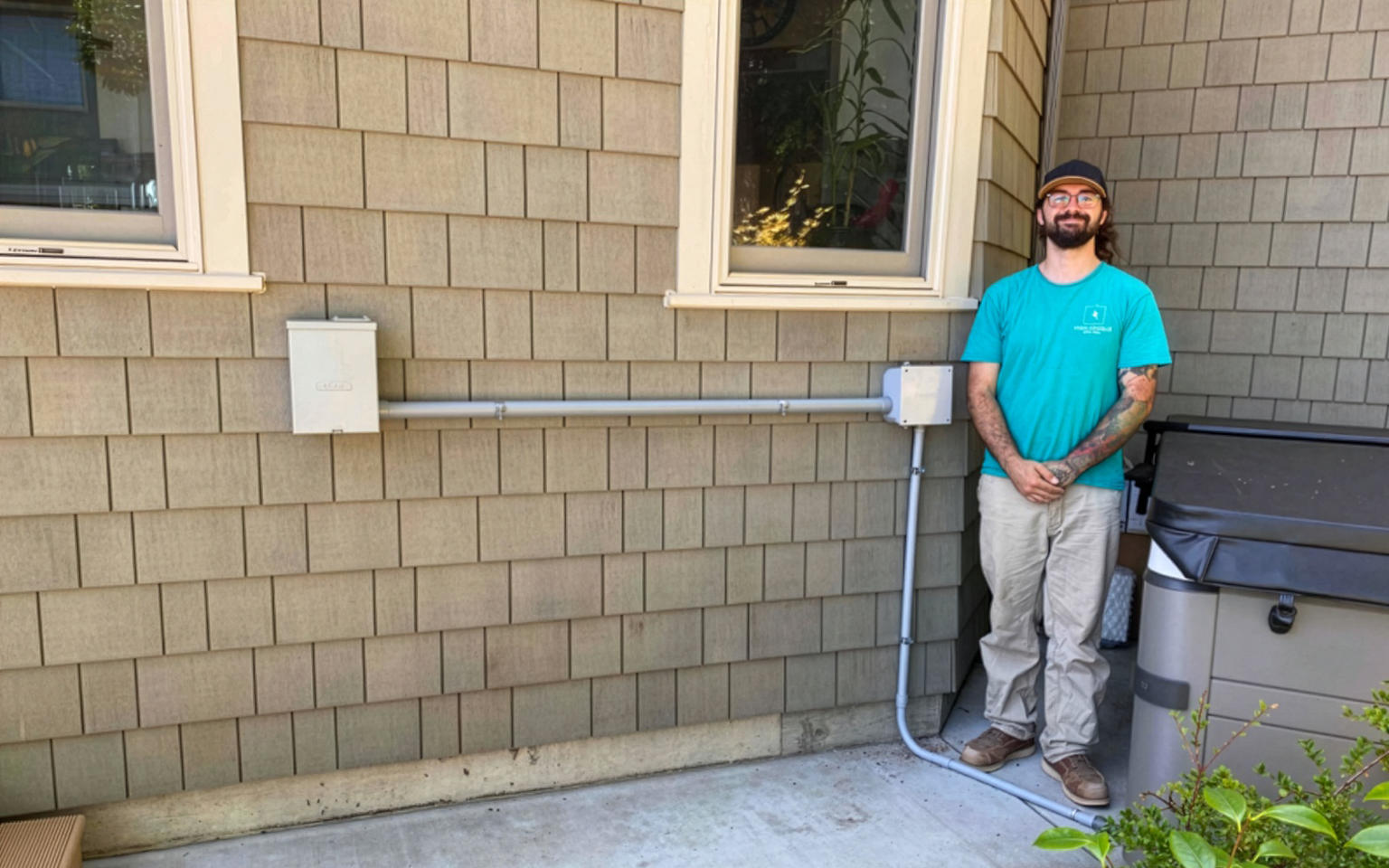 Take Charge Electric electrician standing next to newly installed exterior electrical conduit and hot tub wiring connection.